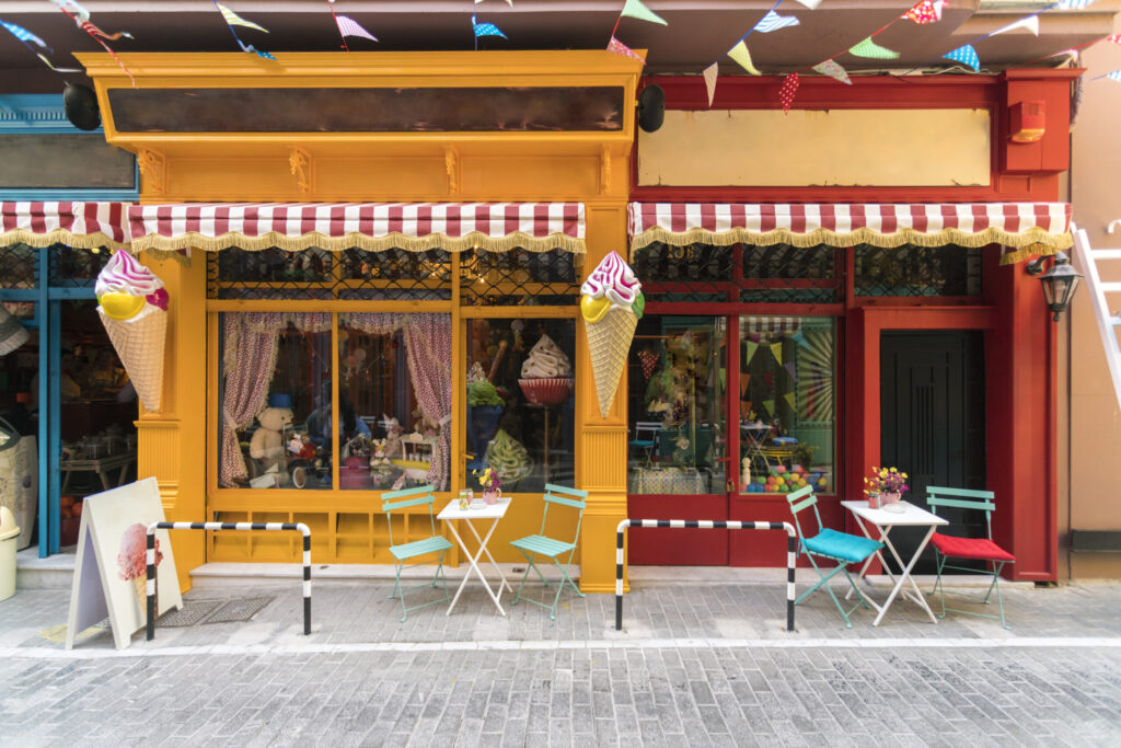 Inviting ice cream shopfront with colorful outdoor seating, decorative ice cream cones, and vibrant awnings, enhancing retail and storefront appeal.