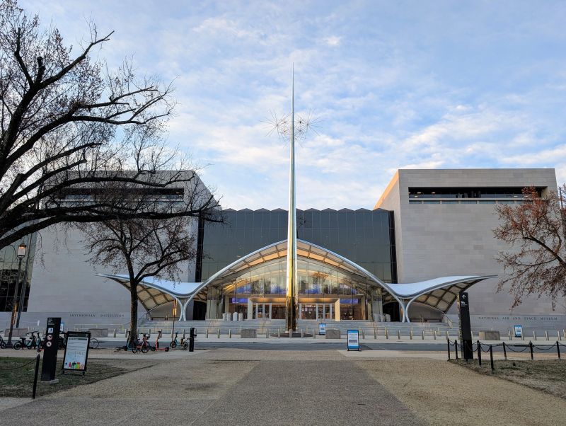 Smithsonian National Air and Space Museum exterior with modern architecture, large glass entrance, and surrounding trees, representing a notable landmark in Washington DC.